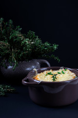 French onion soup in a little ceramic pot against the dark background. Low key photo	