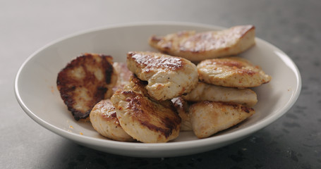 fried turkey fillet pieces falling into white bowl from pan