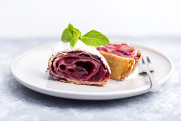 dessert of cherry strudel on a plate, gray concrete background