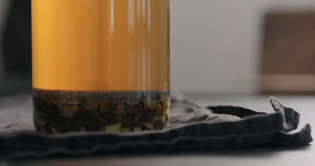 push french press with poured black tea with ginger and seaberry with hot water in glass beaker on kitchen countertop