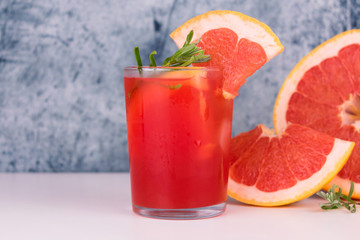 
Grapefruit juice in a glass on a gray background. Copy space.