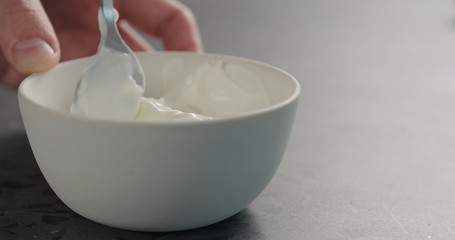 Fototapeta na wymiar pour white yogurt in white bowl on concrete surface