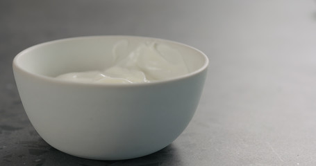 white yogurt in white bowl on concrete surface