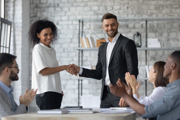 Happy businessman shaking hand and congratulations young african american businesswoman with...