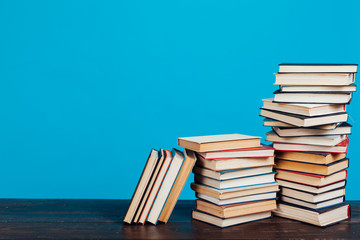 many stacks of educational books for learning preparation for college exams on a blue background