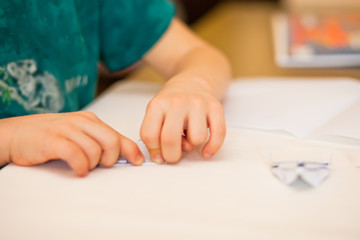 Obraz na płótnie Canvas Children kid hands do origami on the white table.