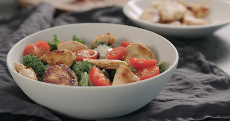 making caesar salad with kale and turkey in white bowl, add tomatoes