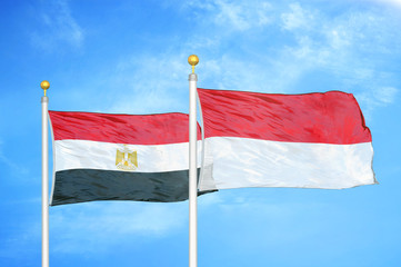 Egypt and Indonesia two flags on flagpoles and blue cloudy sky