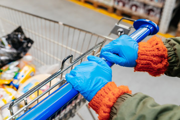 girl in medical gloves in a supermarket with a trolley