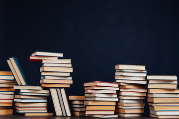 many stacks of educational books for learning preparation for college exams on a black background