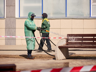 Fototapeta premium Karaganda, Kazakhstan -Meticulous disinfection and decontamination on the streets as a prevention against Coronavirus disease (SARS-Cov-2), COVID-19 outbreak. workers in protective clothing