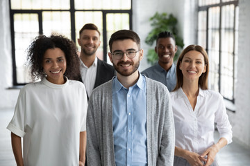 Close up headshot portrait of three happy diverse businesspeople looking at camera. Different smiling employee standing behind of female and male company mentors. Leader of multi-ethnic team concept. - obrazy, fototapety, plakaty