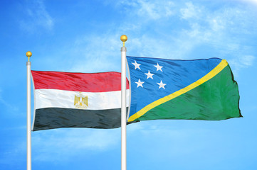 Egypt and Solomon Islands two flags on flagpoles and blue cloudy sky