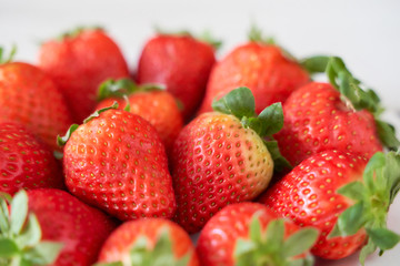 Fresh strawberries on a white plate on a soft wooden base