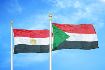 Egypt and Sudan two flags on flagpoles and blue cloudy sky