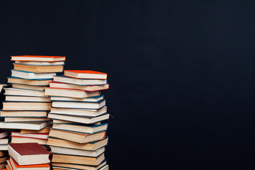 many stacks of educational books for learning preparation for college exams on a black background