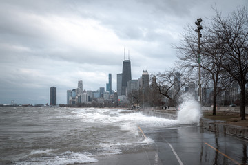 Damaging waves crash against the shoreline and erode the lakefront bike path or trail with Chicago...