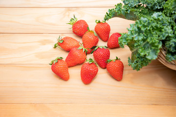 Top view, Group of strawberries, frillice Iceberg Lettuce in a wooden box placed on the table. The produce from the garden is fresh and non-toxic. organic fruit. Collect fresh organic produce