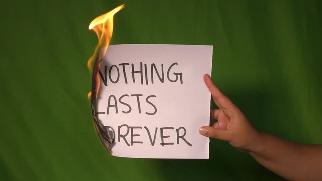 A hand holds the burning paper with nothing lasts forever text word on it.