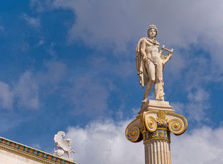 Apollo white marble statue on Ionian style column and small Sphinx under blue sky with some clouds