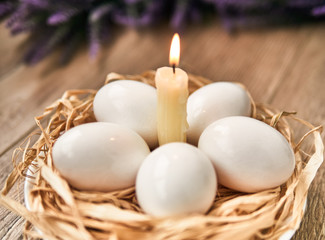 Obraz na płótnie Canvas White Easter eggs with lighting candle. Happy Easter Concept. Congratulations Easter card
