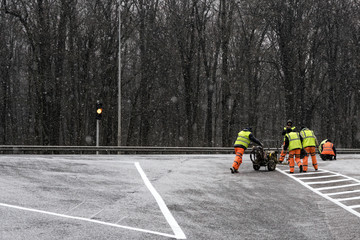 A group of repairmen performs repairs on a section of the road in winter