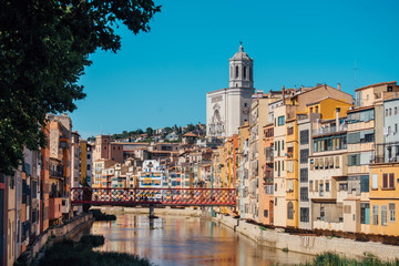 Fototapeta na wymiar Colorful yellow and orange houses and bridge Pont de Sant Agusti reflected in water river Onyar, in Girona, Catalonia, Spain.