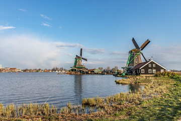 Fototapeta na wymiar old traditional wooden wind mills, blue sky, clouds and water, rural landscape in netherlands on springtime