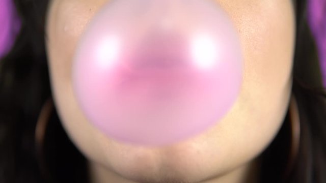 Young woman blowing bubble gum, smiling, pink lipstick, mouth close up portrait