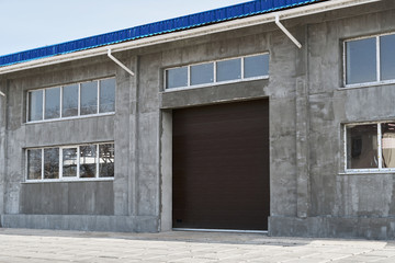 construction or renovation of a single-story building with a large gate, such as a garage or repair shop, windows and gray plaster