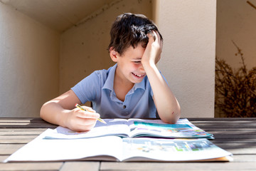 School boy studying book and doing homework and laughing and smiling