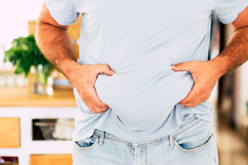 Caucasian fat man hold his belly with hands - diet and healthy lifestyle concept - junk food...