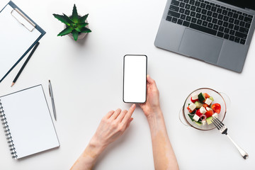 Female reading text message on cell phone during having breakfast