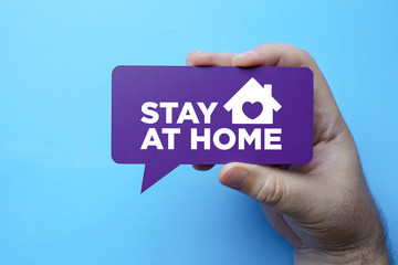 Hand holding speech bubble with stay at home.