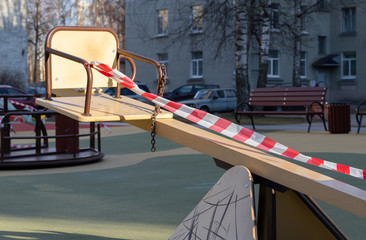 Ban on children's playgrounds during the COVID-19 pandemic. The children's swing is wrapped with signal tape. The Playground is closed due to isolation for non-proliferation of coronavirus.