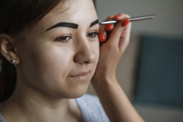Obraz premium Eyebrows and eyes close-up. The master paints eyebrows with henna, paints with a brush in the salon . Brow architecture. Selective focus
