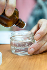 close up of pouring essential oil a jar of cream