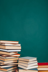 many stacks of educational books for learning preparation for college exams on a green background