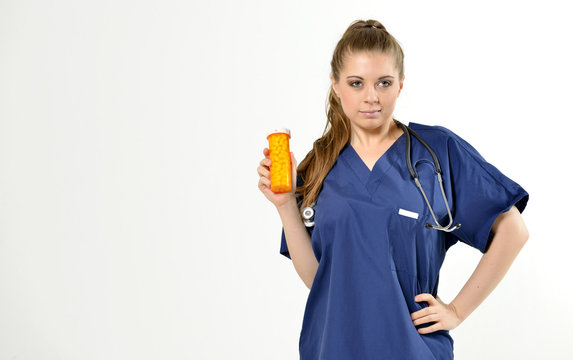 Beautiful young female medical professional with stethoscope smiling as she holds a bottle of pills - studio - no PPE present