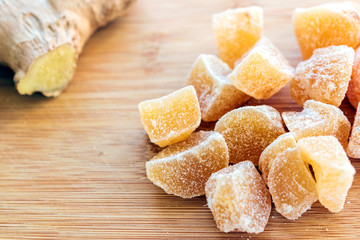 close up of home made ginger candies and fresh ginger on wooden table.