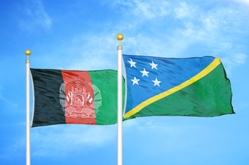Afghanistan and Solomon Islands  two flags on flagpoles and blue cloudy sky