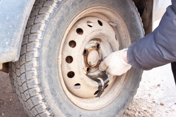 a man unscrews the bolts on the wheel of a car. wheel replacement