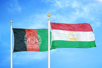 Afghanistan and Tajikistan  two flags on flagpoles and blue cloudy sky