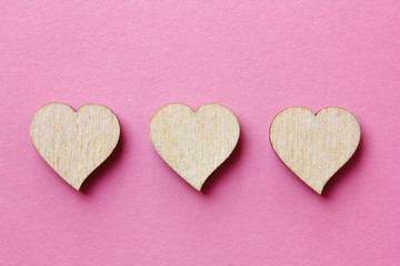 three heart shaped wooden blocks for icons  on a pink background. Customer service experience and satisfaction survey concept