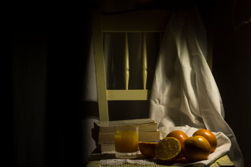 group of oranges on chair with a glass of oranges juice