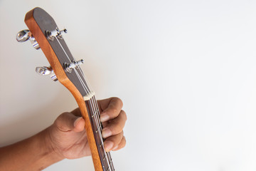 Fototapeta premium hand hold neck of ukulele it for playing on white background