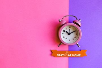 Stay at home. Alarm clock on colored background.