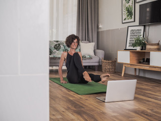 happy and smiling women looking into the laptop in doing a fitness pilates workout in her living room at home