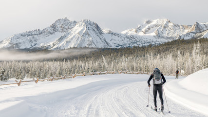 Cross Country skier follows a road that leads to a winter mountain range