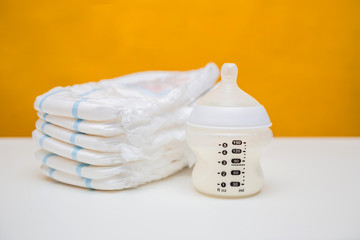 Diapers and baby food in a bottle on the background